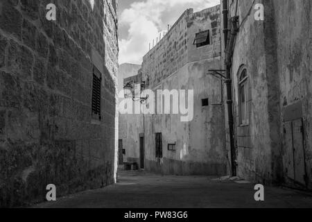 Eine typische alte Gasse in Siggiewi, Malta in Schwarz und Weiß mit alten Häusern in Schwarzweiß. Stockfoto