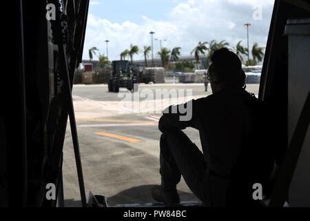 Staff Sgt. John Pittman, 41 Airlift Squadron Lademeister, wartet für das Personal zu kommen und ein eigenes Route Patienten Staging System aus einer C-130 J in Little Rock Air Force Base, Arche, Okt. 1, 2017 stationierten Offload, San Juan, Puerto Rico. Die 41 WIE transportiert auch Personal aus der 375. und 43. Aeromedical Evacuation Schwadronen und eine Critical Care Air Transport Team aus der 59 medizinischen Flügel, ärztliche Behandlung zu aeromedical Umsiedler Patienten zu geben. Stockfoto