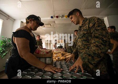 Us Marine Corps Sgt. Pedro L. Emmanuelli, rechts, eine Landung Support Specialist mit loslösung 1, Landung Support Unternehmen, Bekämpfung Logistik Regiment 45, 4 Marine Logistik Gruppe, seine Dienstleistungen Freiwilligenarbeit mit dem 26 Marine Expeditionary Unit (MEU), spricht mit Freiwilliger an einer lokalen Heilsarmee als Teil der Hilfsmaßnahmen für die Opfer von Hurrikan Maria in Fajardo, Puerto Rico, Oktober 3, 2017. Die 26. MEU, zusammen mit den lokalen Behörden und anderen Verteidigungsministerium Dienstleistungen, unterstützt die Leitung Bundesamt, Federal Emergency Management Agency, die in der humanitären Hilfe Stockfoto
