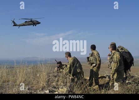 Soldaten mit 2-10 Assault Helicopter Bataillon, 10 Combat Aviation Brigade, beobachten eine UH-60 Blackhawk bieten Antenne Sicherheit für Rumänische pararescue Kräfte in Babadag, Rumänien, 3. Oktober 2017. Der Zweck dieser simulierten abgestürzten Flugzeuge Ausbildung Übung war von Fähigkeiten im Überleben, Steuerhinterziehung, Widerstand und Flucht Verfahren bauen, 10 CAB Soldaten mit dem csel System vertraut zu machen und Personal zu entwickeln Recovery Verfahren zwischen den NATO-Verbündeten. Stockfoto