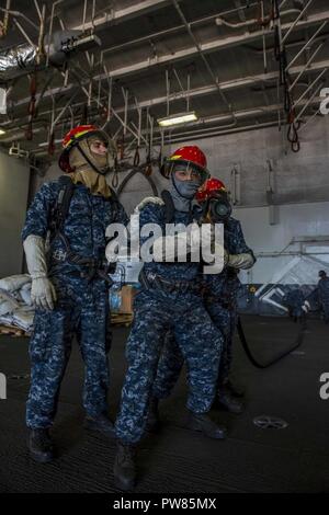 NORFOLK, Va (Sept. 28, 2017) Segler Mann einen Schlauch vor der Simulation ein Brand während einer allgemeinen Quartal bohren an Bord der Flugzeugträger USS George H.W. zu setzen Bush (CVN 77). Das Schiff ist im Hafen Norfolk, Virginia, die Durchführung von routinemäßigen Wartung nach einer 7-monatigen Einsatz zur Unterstuetzung der Maritime Security Operations und Theater Sicherheit Zusammenarbeit in den USA am 5. und 6 Flotte Verantwortungsbereiche. Stockfoto