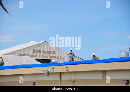 Mitglieder der 156 Tiefbau squadron Reparatur des Dachs durch Hurrikan Maria an der Muniz Air National Base, Puerto Rico beschädigt mit einer der weithin anerkannten FEMA blaue Blätter. Stockfoto