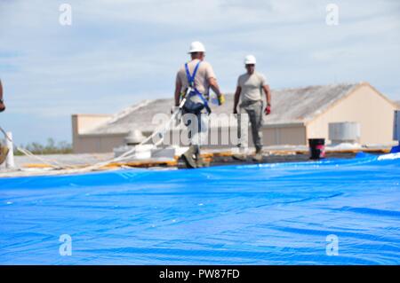 Mitglieder der 156 Tiefbau squadron Reparatur des Dachs durch Hurrikan Maria an der Muniz Air National Base, Puerto Rico beschädigt mit einer der weithin anerkannten FEMA blaue Blätter. Stockfoto