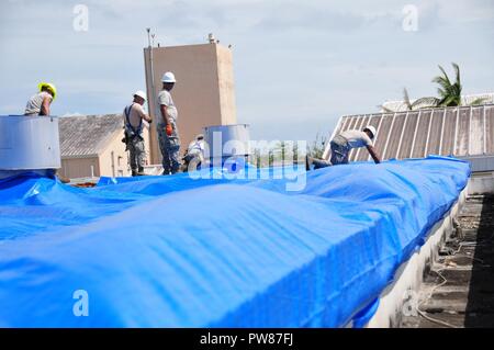 Mitglieder der 156 Tiefbau squadron Reparatur des Dachs durch Hurrikan Maria an der Muniz Air National Base, Puerto Rico beschädigt mit einer der weithin anerkannten FEMA blaue Blätter. Stockfoto