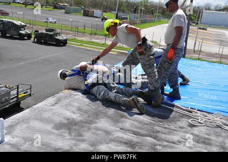 Mitglieder der 156 Tiefbau squadron Reparatur des Dachs durch Hurrikan Maria an der Muniz Air National Base, Puerto Rico beschädigt mit einer der weithin anerkannten FEMA blaue Blätter. Stockfoto