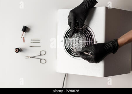 Nagelpflege. Werkzeuge für die Nägel. Weibliche Hände halten Schere über einen Staubsauger. Stockfoto