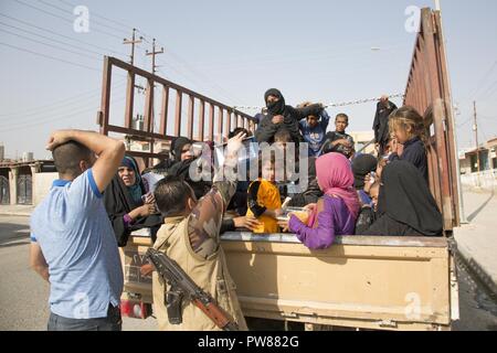 Ein peshmerga Soldat der intern Vertriebenen zu einem Screening Punkt verläuft, Wasser, dass er sein eigenes Geld verwendet für die Gruppe in der Nähe von Dibis, Irak, 30. September 2017, das transportiert wird, zu kaufen. Die internationale Hilfe Gruppen arbeiten mit der Regierung des Irak zu Hilfe und Unterstützung für Binnenvertriebene zur Verfügung zu stellen. Die Regierung Iraks und die lokalen Regierungen in Zusammenarbeit mit der internationalen Gemeinschaft arbeiten Dienstleistungen und kehren die Menschen in ihre Häuser so schnell wie möglich wiederherzustellen. Stockfoto