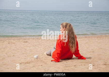 Frau trinkt heißen Kaffee oder Tee am Strand 1. Stockfoto