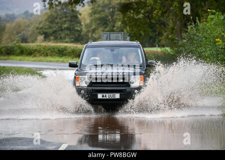 Ein Land Rover fährt durch einen überfluteten Abschnitt der A4077 durch Crickhowell, Wales, wo eine gelbe Wetter Warnung in Kraft ist in der gesamten Region als schwerer Regen verursacht überschwemmungen. Stockfoto