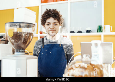 Gastfreundliche barista lächelnd und stand hinter der Theke. Stockfoto