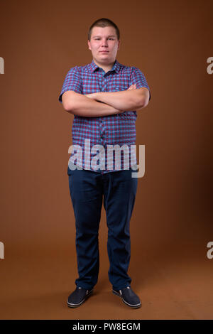 Studio für übergewichtige junge Menschen gegen den braunen Hintergrund Stockfoto