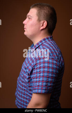 Studio für übergewichtige junge Menschen gegen den braunen Hintergrund Stockfoto