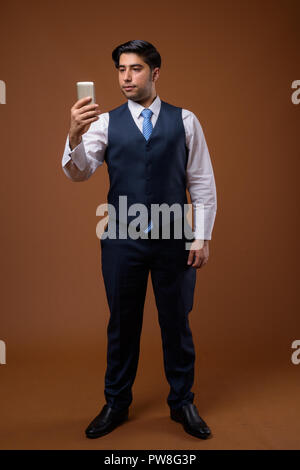 Junge hübsche Iranische Geschäftsmann gegen braunen Hintergrund Stockfoto