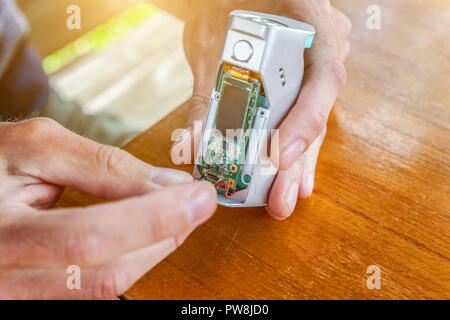 Mann die Hände zur Festsetzung moderne Vaporizer e-cig Gadget vape e-liquid. Wartung elektronischer Geräte mech Mod vaping Gerät. Vaper Gerät reparieren Servi Stockfoto