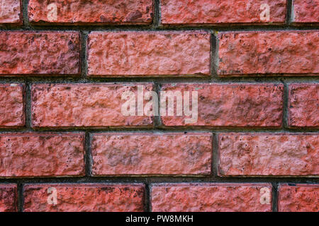 Eine Nahaufnahme von einem roten gemauerte Wand. Bricky Textur. Mauerwerk Gelenkwelle Hintergrund. Nähte auf eine Wand. Bausteine der Ziegel in Zaun Bau. Zoomen Stockfoto