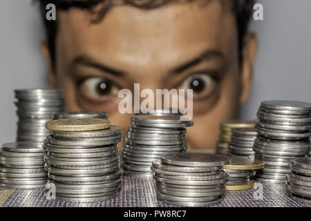 Fokus auf Münze. Ein reichhaltiges gierig älterer Mann schaut auf Münzen. Der Kollektor sieht seinen Reichtum. Ein älterer Mann in Metall Geld starrte auf den Boden. Stockfoto