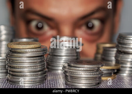 Fokus auf Münze. Ein reichhaltiges gierig älterer Mann schaut auf Münzen. Der Kollektor sieht seinen Reichtum. Ein älterer Mann in Metall Geld starrte auf den Boden. Stockfoto