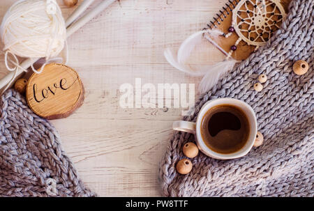 Gemütliche Zusammensetzung mit Kaffee, aus Gewirken Elemente aus Merinowolle auf einer hölzernen Hintergrund. Ein Foto in einem hygge Stil. Stockfoto