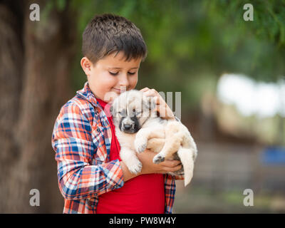 Kind umarmt einen kleinen Welpen. Kinder lieben Tiere Stockfoto