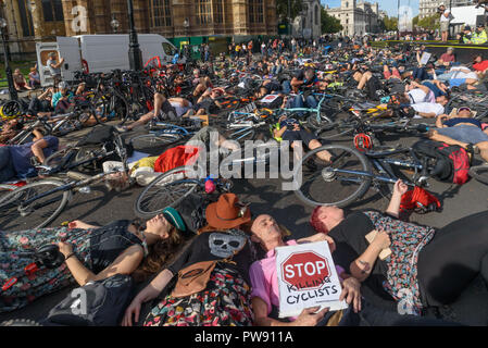 London, Großbritannien. 13. Oktober 2018. Leute, einschließlich Donnachadh McCarthy (in rosa Hemd) der Töten Radfahrer nehmen an einem 10-minütigen sterben - in außerhalb des Parlaments am Ende der Trauerzug der Radfahrer hinter einer von Pferden gezogenen Leichenwagen das Versagen der Regierungen von allen großen Parteien zu markieren umfassende Maßnahmen zum sicheren Radfahren. Töten Radfahrer Anruf für £ 3 Milliarden jährlich in einem nationalen geschützt Radwegenetz und für dringende Maßnahmen der giftige Luftverschmutzung aus Diesel und Benzin Fahrzeuge, die Zehntausende Menschen jedes Jahr tötet zu reduzieren investiert werden, und Stockfoto