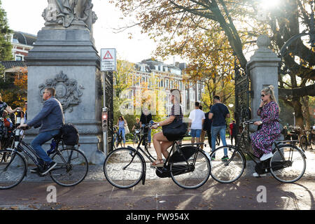 Den Haag, Niederlande. 13 Okt, 2018. Die Menschen fahren Fahrrad auf einer Straße in Amsterdam, Niederlande, Okt. 13, 2018. Credit: Zheng Huansong/Xinhua/Alamy leben Nachrichten Stockfoto