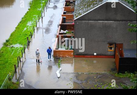 Samstag, 13. Oktober 2018. Tonna, South Wales, UK. Überschwemmung bewirkt die Dörfer von Aberdulais und Tonna in der Neath Valley in South Wales nach Sturm Callum starker Regen und Wind in den Bereich des Flusses Neath brachte Bersten zu erreichen. Abgebildet sind die Bewohner von Canal Seite, weckte zu finden, ihre Eigenschaften und Gärten überflutet. Zwei Bewohner stehen außerhalb der überfluteten Häuser. Credit: Robert Melen/Alamy leben Nachrichten Stockfoto