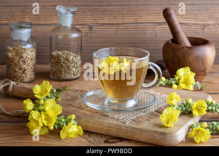 Eine Tasse Kräutertee mit frischen Königskerze Blüten auf einem rustikalen Hintergrund Stockfoto