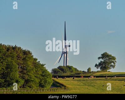 Ein Paar von Windenergieanlagen Turm über der Landschaft von Weidevieh auf einem Bauernhof in Northumberland, England, UK. Stockfoto