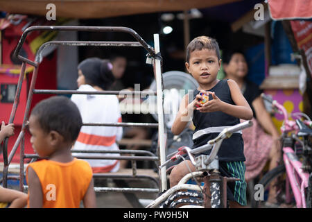 Junge Filipino Junge sitzt auf einem Dreirad im CO2-Markt, Cebu City Stockfoto