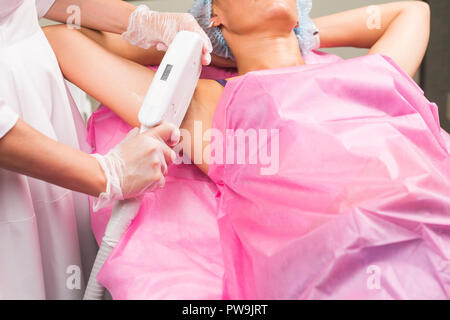 Wellness, Menschen und Kosmetologie Konzept - Frau mit unterarm Laser Haar Entfernung Epilation. Stockfoto