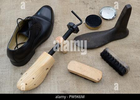 Verschiedene Objekte für die Wartung und Reparatur von Schuhen, einschließlich, Schuhspanner, letzte, Polieren und Bürsten neben einem Mans schwarz Schuh. Stockfoto