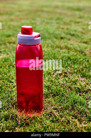 Rotes Wasser bootle auf dem Gras in einem Park Stockfoto