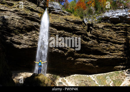 Frau in gelber Jacke stand vor der Wasserfall Pericnik, Slowenien Stockfoto
