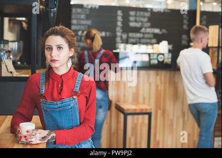 Ziemlich kaukasische Mädchen mit Glas Cappuccino und zwei junge Menschen im Kaffee Bar Stockfoto