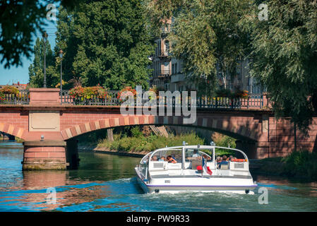 Touristische Unterhaltung in Straßburg, Frankreich mit einer Bootsfahrt auf der Ill, unter einem vintage Brücke und Bäume, an einem sonnigen Tag im Sommer. Stockfoto