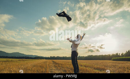 Freudige Geschäftsmann seinen Erfolg feiern im schönen Abend Natur wirft seine Jacke hoch oben in der Luft unter der majestätischen cloudscape. Stockfoto