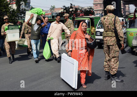 Wahlkommission Pakistans (ECP) Personal ist die Wahlurnen und andere Elemente zu einem Wahllokal am Regierung Islamia High School vor den Wahlen wurde unter der Aufsicht von Pak Armee in Lahore am 13. Oktober 2018. Pak Armee und Pakistanischen Wahl präsidierenden Beamten tragen Wahl Materialien für eine Nachwahl nach Erhalt von der Verteilung von Punkt in Lahore, über 100 Kandidaten wetteifern für 35 National Assembly und provinzversammlung Sitze in der Wahl für den 14. Oktober vorgesehen. (Foto von Rana Sajid Hussain/Pacific Press) Stockfoto