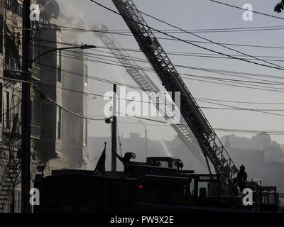 Feuerwehrautos mit ausgebauter Leitern parkten vor einem tödlichen Feuer in einem Haus auf halber Höhe in der San Pablo Ave. 2551 in West Oakland am 27. März 2017. Stockfoto