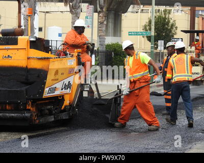 Ein Arbeiter Schaufeln Asphalt auf der 51st Street in der Nähe von Martin Luther King Jr. in Oakland, Kalifornien, während belagserneuerung die Straße als Teil des Jahresberichts der Stadt "Schlagloch blitz' auf August 3, 2017. Stockfoto