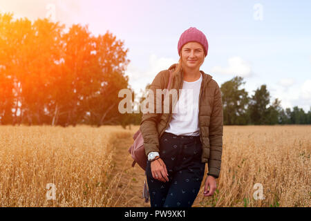 Portrait fröhliche junge Frau mit Brünette Haar in Strick Hut, grünen Mantel und t-shirt Spaß, lächeln und genießen Sie Tag auf dem Feld. Stilvolle hipster woma Stockfoto