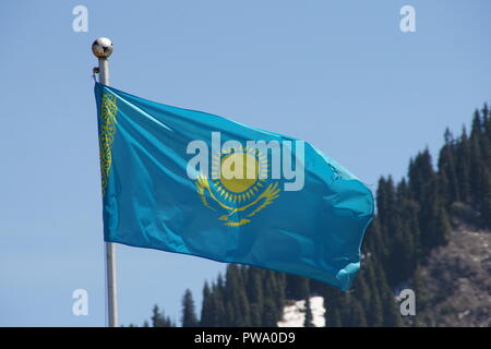 Fahne von Kasachstan in den blauen Himmel und die Berge hinter Almaty Medeo Stockfoto