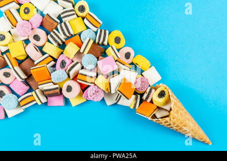 Waffel Kegel mit farbigen Süßholz Candys auf hellblauem Hintergrund. Stockfoto