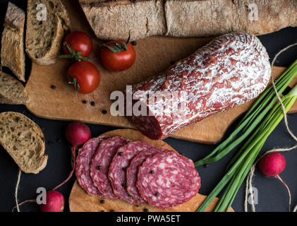 Verschiedene Gemüse, Brot und Wurst auf dunklem Hintergrund isoliert Stockfoto