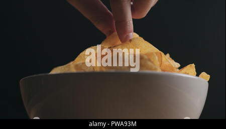 Closeup hand nehmen Potato Chip von weiße Schüssel Low Angle Shot, breite Foto Stockfoto