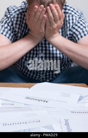 Ein Mann mit Geld Probleme mit Rechnungen stapeln Sie die Tabelle hat Kopfschmerzen. Stockfoto