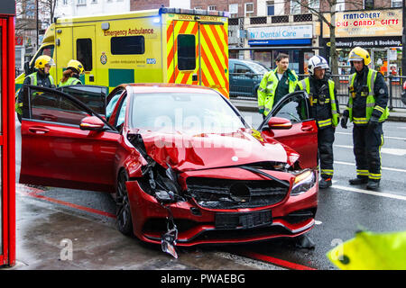 Feuerwehrleute und Sanitäter besuchen einen Straßenverkehr Zwischenfall mit einem roten Mercedes in Holloway, London, UK im Januar 2016. Zum Glück niemand verletzt wurde Stockfoto