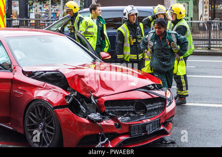 Feuerwehrleute und Sanitäter besuchen einen Straßenverkehr Zwischenfall mit einem roten Mercedes in Holloway, London, UK im Januar 2016. Zum Glück niemand verletzt wurde Stockfoto