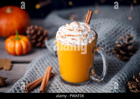 Kürbis Latte mit Gewürzen. Versoffenes Cocktail mit Schlagsahne oben auf einem hölzernen Hintergrund Stockfoto