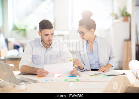 Zwei junge Fachleute diskutieren, Papier und Arbeiten über neue Business Projekt in der Sitzung Stockfoto