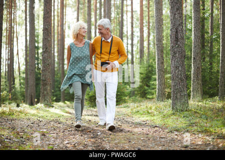 Gerne reifer Mann und Frau in der casualwear hinunter Wald Weg und genießen Sommer Tag Stockfoto